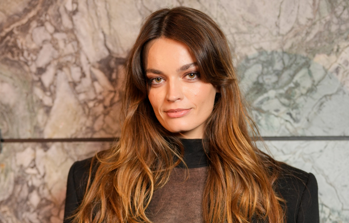 À l'affiche du film Le Monde de Narnia, l'actrice Emma Mackey prend la pose sur le photocall d'un défilé dans un costume noir et top en dentelle.