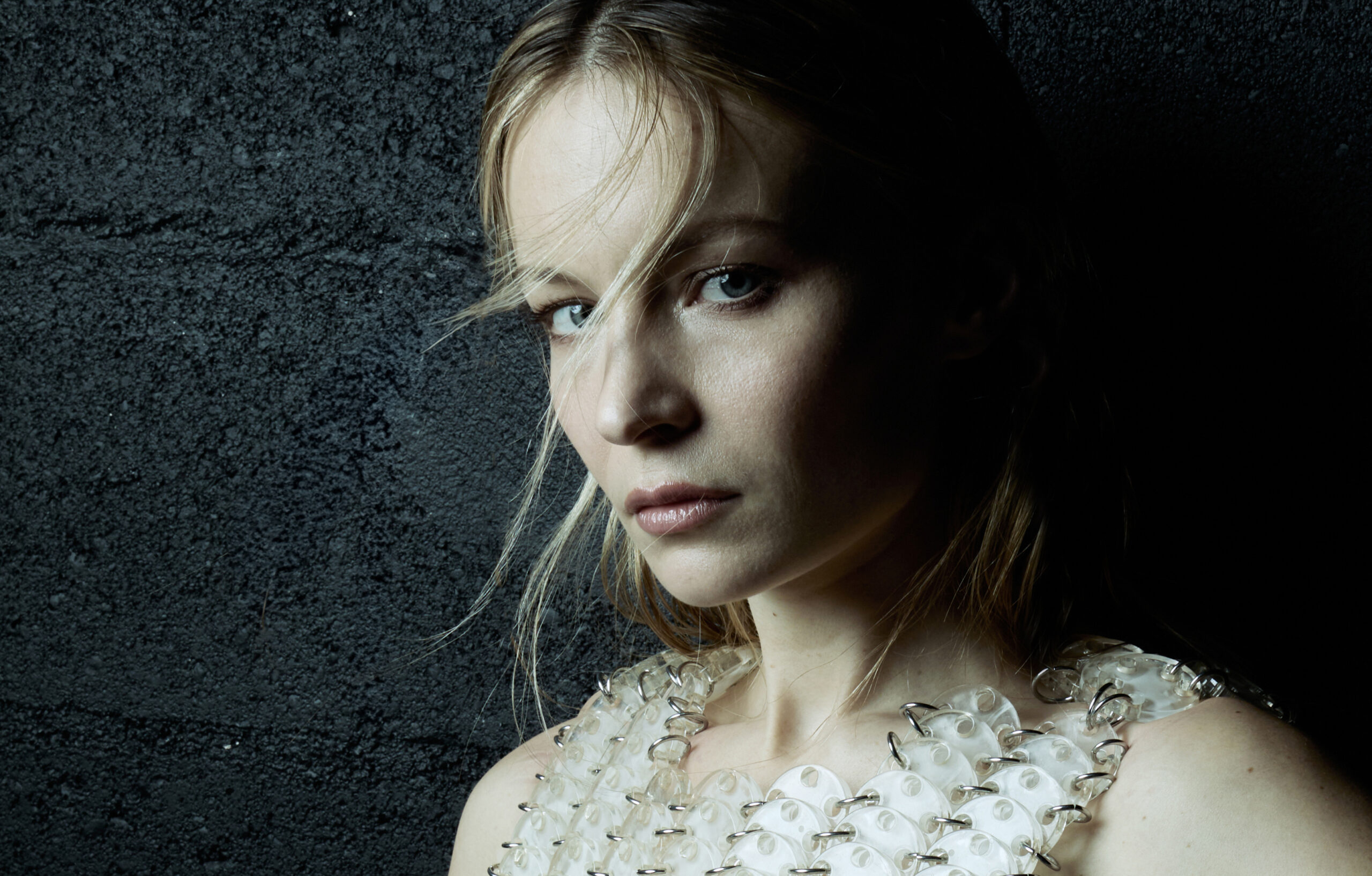 L'actrice Diane Rouxel regarde la caméra, le corps accolé à un mur.